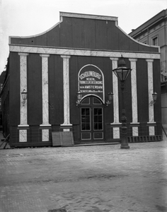 98148 Afbeelding van een theatergebouw met op de toegangsdeur de tekst: Schouwburg/ Nederl./ Tooneelvereeniging van ...